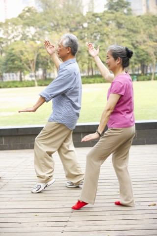 Man and a woman doing Tai Chi movements.