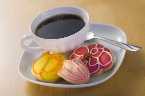White plate with white tea cup and pink and yellow cookies