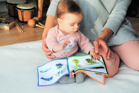 Baby reading board book with parent.  