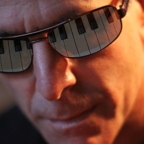 Man wears sunglasses that reflect piano keys.
