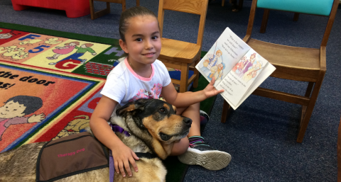 Child reading a book to Luna.