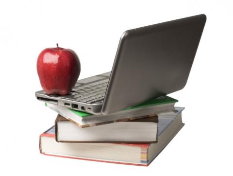 Open laptop computer on a stack of books with a red apple on top