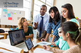 Teacher and teens looking at computer monitor and smiling and working