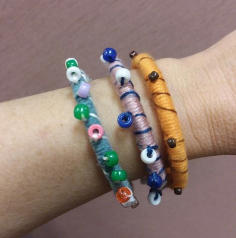 Wrist with three bracelets made from yarn and beads