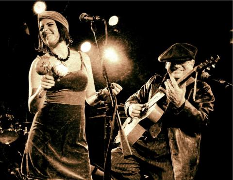 Sepia-toned photo of a woman with a microphone and a man playing guitar