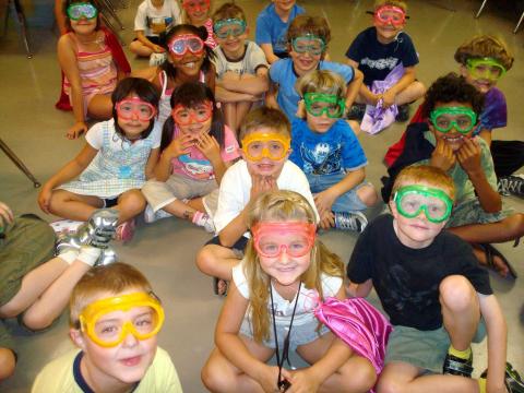 Group of young children, all wearing safety goggles, ready to learn about Science