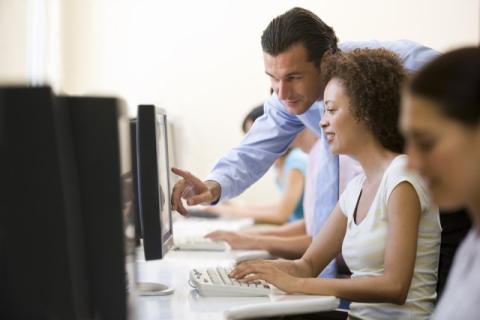 woman at computer with man helping over her shoulder
