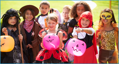 Group of children wearing Halloween costumes and carrying pumpkin shaped candy buckets