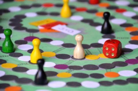 Board game close up with a colorful board, red die, game pieces in different colors