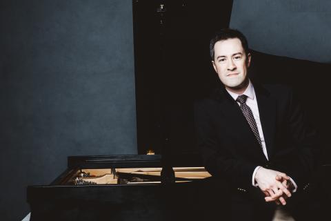 Andrew Brownell leaning on a piano