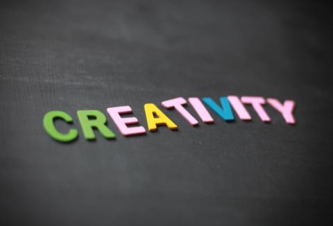 The word CREATIVITY spelled out in multicolored letters on a dark grey background