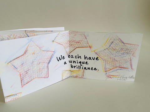 Handmade book with drawn stars and "we each have a unique brilliance" written on it