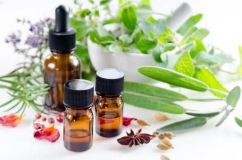 Small brown bottles surrounded by fresh green herbs