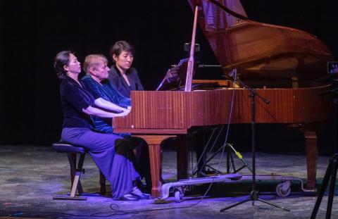 Helena Wei playing the piano with two other women