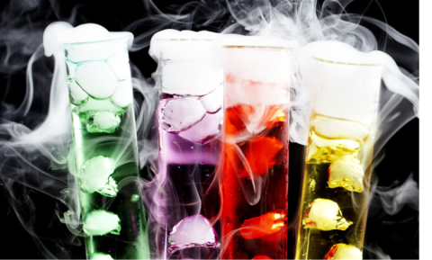 Green purple, red, and yellow colored liquid vials with dry smoke billowing out.