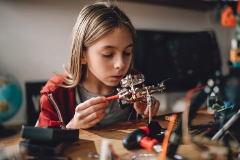 Teenage girl building a small robot