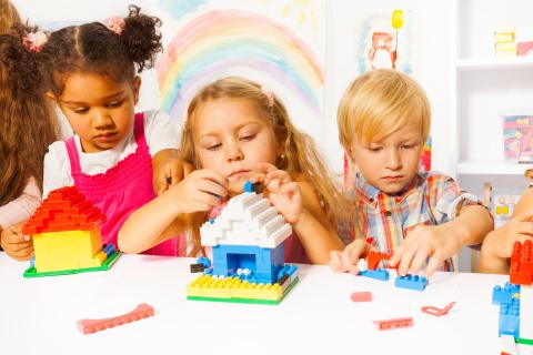 Three children building with lego bricks. 