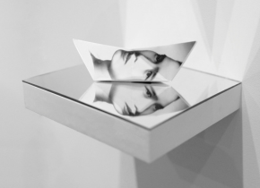 Picture of an old photograph folded into a paper boat and placed on top of a mirror by artist Rizzhel Javier.