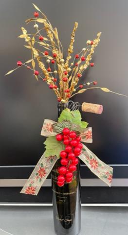 Bottle decorated with red bow and artificial plants