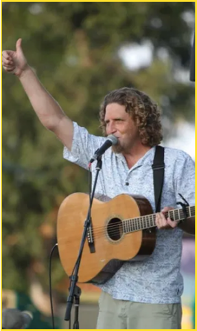 Man holding guitar and waving hand