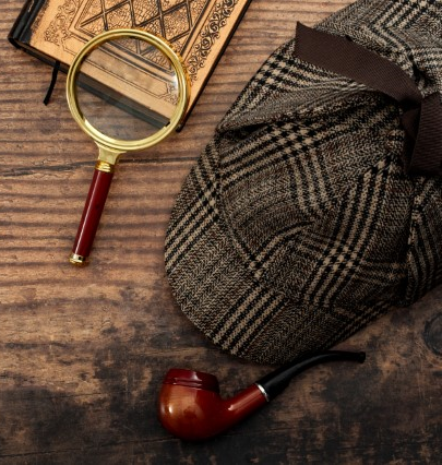 magnifying glass, detective hat and paper on a table