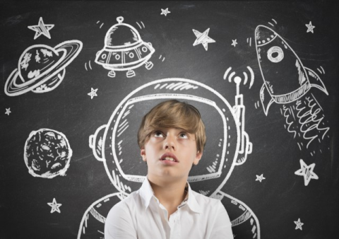 boy in front of chalkboard with space-related drawings