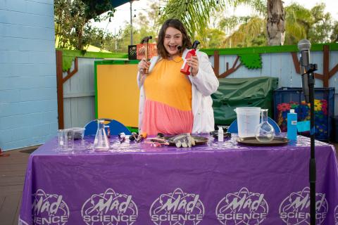 Smiling female scientist at an outdoor booth with beakers on the table