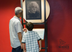 Boy and a man look at a science exhibit on pixels featuring Albert Einstein's face.