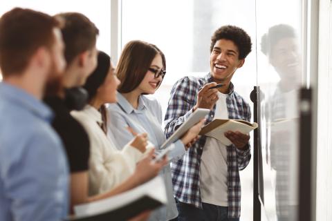 Group of young adults collaborating together at a whiteboard.