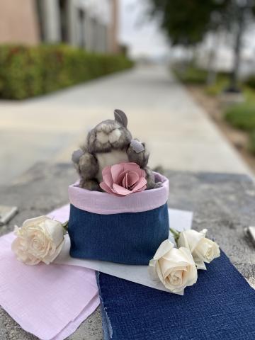 Upcycled denim basket with flowers and stuffed animal.