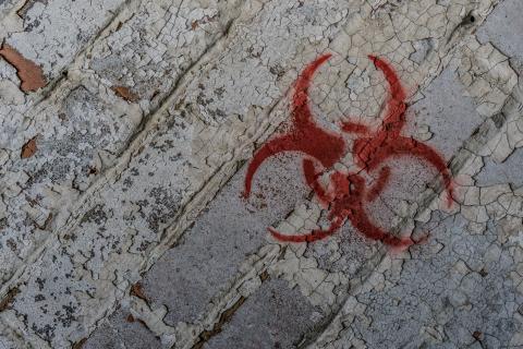 gray brick background with spray painted red dangerous chemical symbol