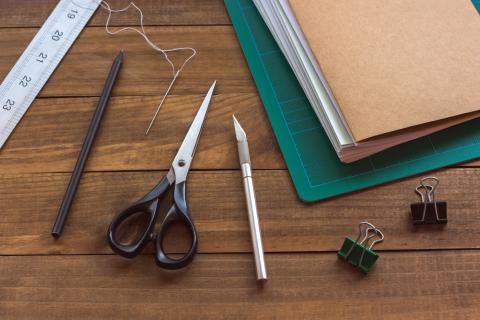 ruler, bound paper, scissors,, clips on a table