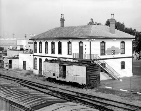 An old black and white photo of an old train yard and train station.