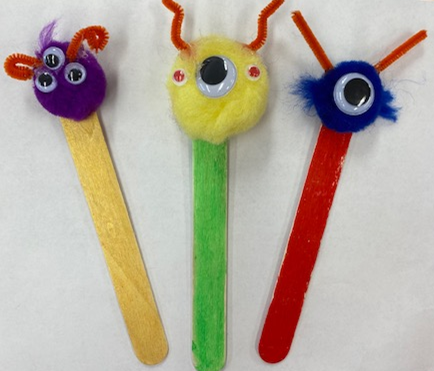 Three examples of monster bookmarks made with craft sticks, pompoms, and chenille stems
