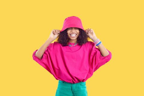 Young teen girl wearing a bright pink shirt and bucket hat