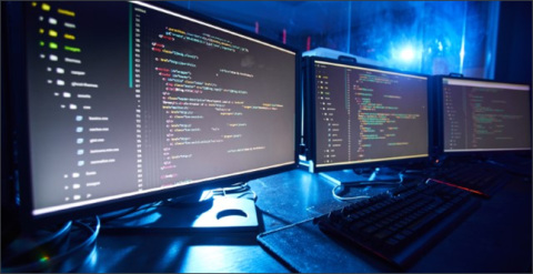 Three computer monitors with coding language displayed with a blue light background