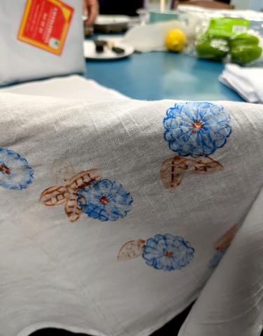 White tea towel with a flower design stamped/painted in blue and copper-color