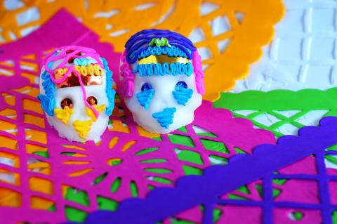 Two white sugar skulls with colorful icing decorations for dia de los muertos