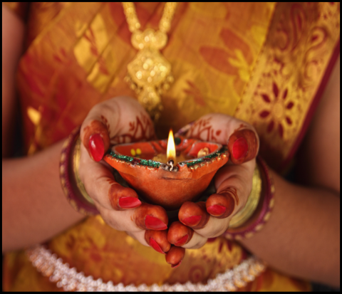 Indian woman holding Diwali orange diya