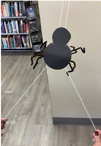 Paper spider sliding up a string