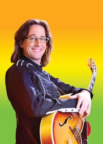 Ralph Covert holding a guitar on a multicolored background