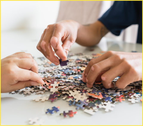 Three hands flipping over jigsaw puzzle pieces.