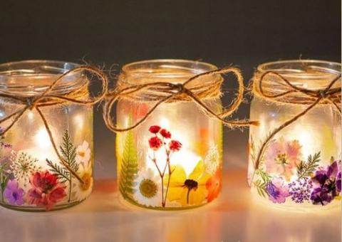 Three glass candle holders decorated with pressed flowers. 