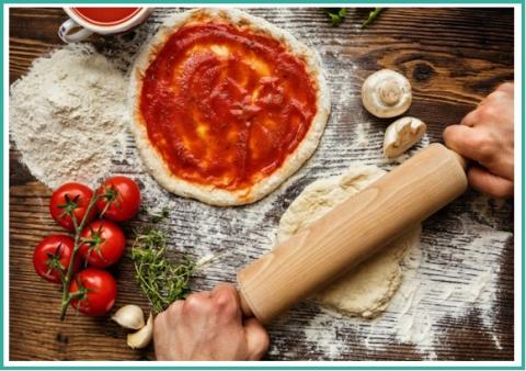 Photo of someone rolling out pizza dough