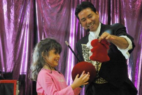 Allen the magician completes appearing dove trick with child wearing pink sweater