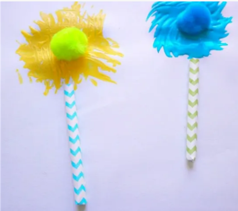 A yellow Truffula tree and a blue Truffula tree made with fork painting, straws, and pompoms