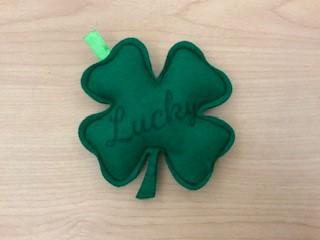 A green, felt, 4-leaf clover inscribed with the word "lucky."