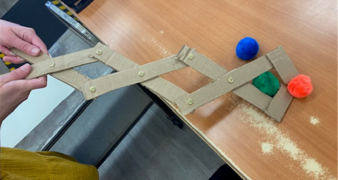 Cardboard articulated grabber picking up a pompom 