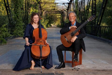 Outdoor photo of a a seated woman with a cello and a man with a guitar