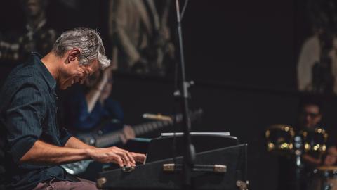 Photo of a man smiling while playing keyboards